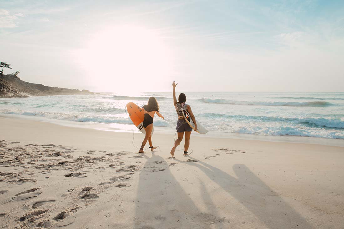 two women with surfboards walking toward the ocean